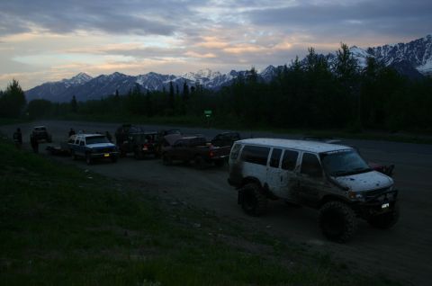 2003 Jeep TJ - Off-road vehicles gathered on a dirt road with a mountain range visible in the background at dusk.
