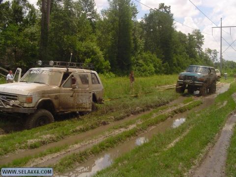 1995 Ford Bronco - Two Ford Broncos navigate a muddy off-road course, one requiring assistance from the other.