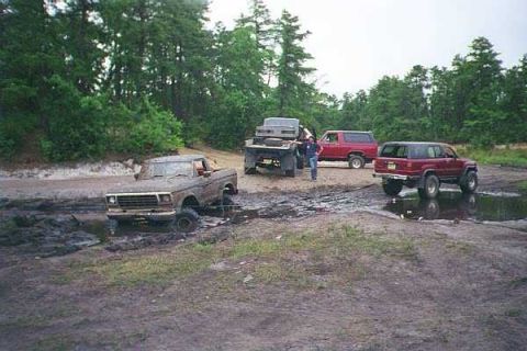 1990 Ford Bronco - Several off-road vehicles are stuck in the mud during an outing.