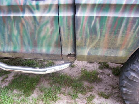 1990 Ford Bronco - Close-up of a truck's side panel camouflage paint and a visible rust spot near the wheel well.