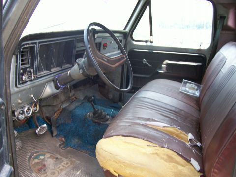 1990 Ford Bronco - The interior of this truck shows significant wear, including torn upholstery and faded carpet, with a 'FORD' logo visible on the floor mat.