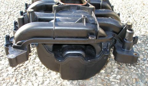 1998 Ford Crown Victoria - This is a close-up view of a black plastic engine intake manifold, likely a replacement part.