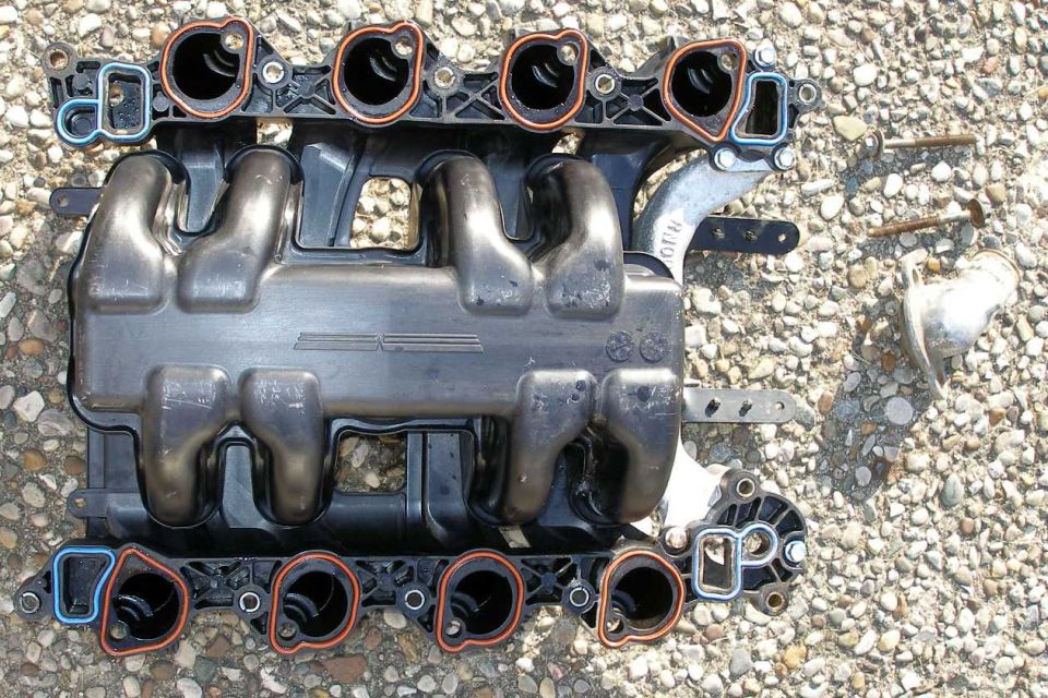 Underside of a black Ford modular V8 intake manifold with orange and blue port gaskets