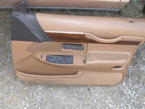 1998 Ford Crown Victoria - A tan interior door panel, likely from a sedan, wood grain trim and a speaker cutout.