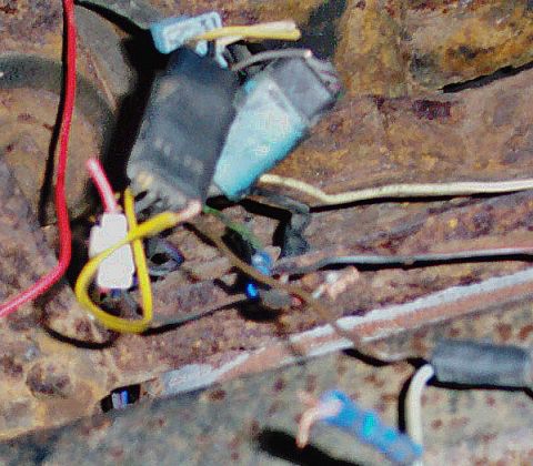 1978 Ford Bronco - Vehicle wiring harness with multiple colored wires connected to electrical components on a rusty surface.