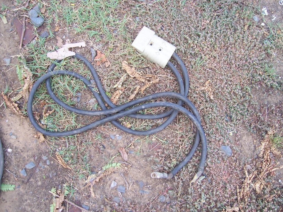 Jumper cables with a large white connector and metal clamps on the ground