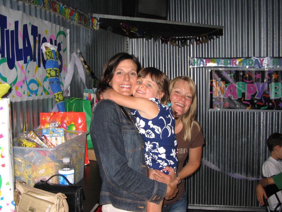 Three people smiling at a birthday party with decorations and gifts