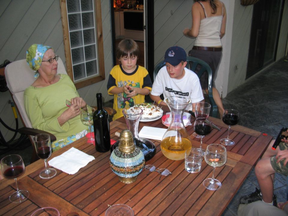 People gathered around a wooden table with wine and food