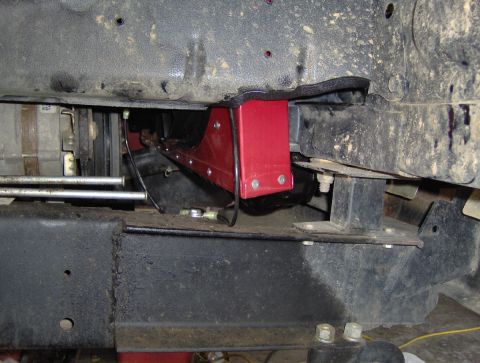 1978 Ford Bronco - Close-up view of a red bracket being installed onto the vehicle's frame.