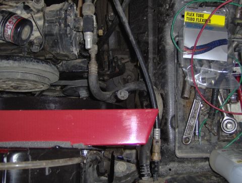1978 Ford Bronco - Close-up view of engine bay parts and tools, including a yellow package labeled 'FLEX TUBE TUBO FLEXIBLE'.