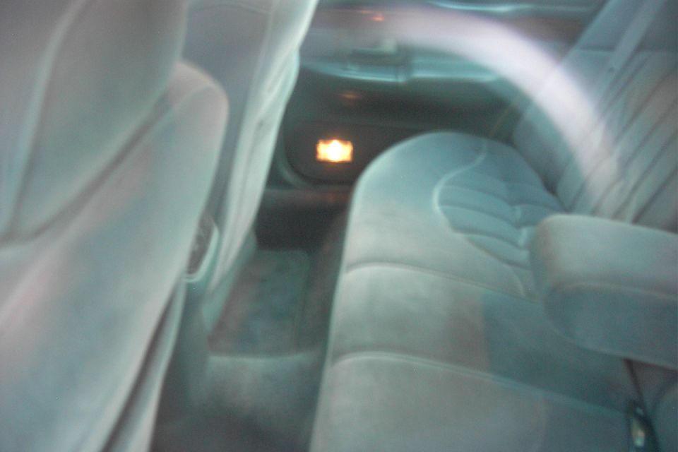 Dark blurry interior view of gray cloth rear seats with a glowing courtesy light
