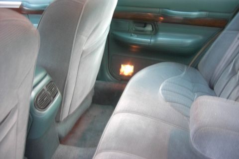 1996 Mercury Grand Marquis - Interior view of a car's back seat, highlighting the door panel details and illuminated footwell light.