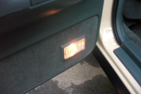 1996 Mercury Grand Marquis - Interior door panel with a lit courtesy lamp, showing part of the door frame and trim.