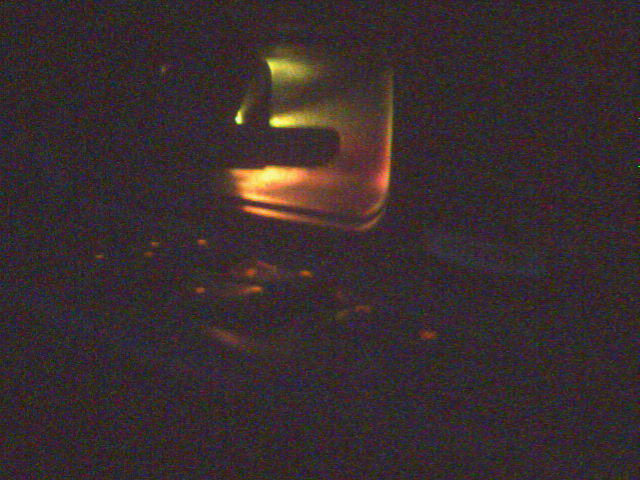 Dark blurry image with faint orange and yellow glare, no clear subject