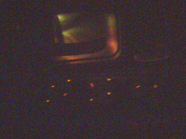 Dark blurry image with faint orange glows and no clear subject