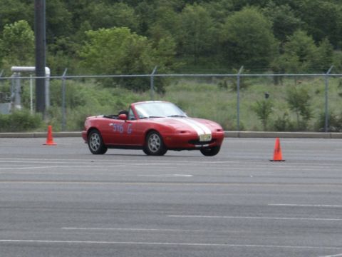 2001 Mercury Grand Marquis - A red convertible sports car with white racing stripes navigates a course marked by orange cones.