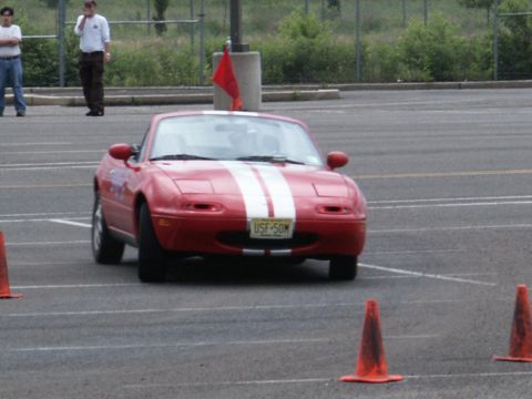 2001 Mercury Grand Marquis - Red convertible sports car with white racing stripes navigates a course marked by orange cones.
