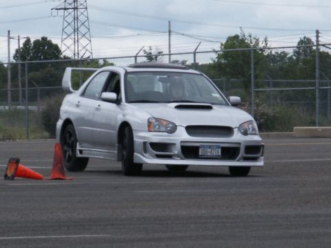 2001 Mercury Grand Marquis - A silver Subaru Impreza WRX is seen on a track with traffic cones, indicating a performance driving event.
