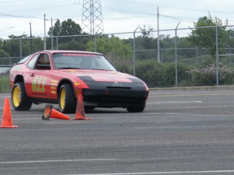 2001 Mercury Grand Marquis - A red Porsche 944 with racing decals and yellow wheels is seen on an autocross course.