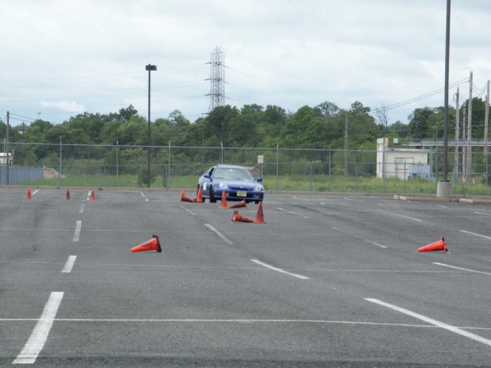 Blue coupe navigating a cone course in a parking lot