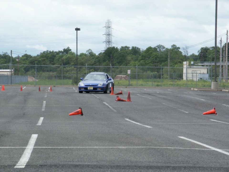Blue coupe driving through an autocross course marked by orange cones