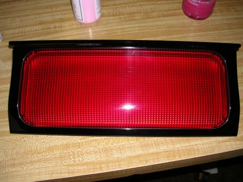 1996 Ford Probe - A red reflector part is shown against a wooden background.