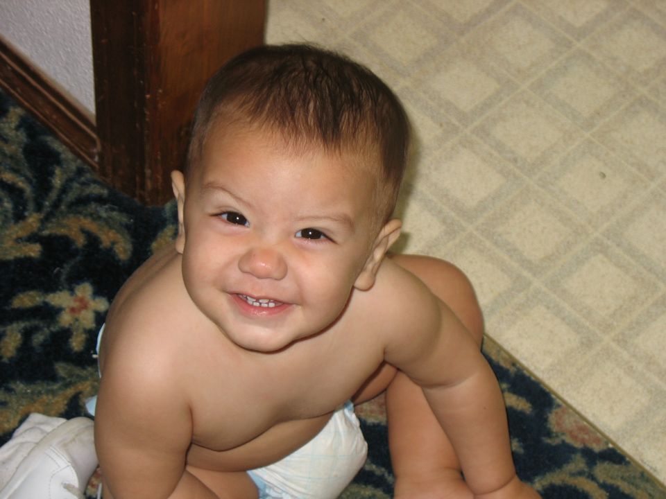 Baby in a diaper smiling, with a Supermotors.net watermark