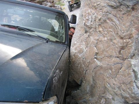 1994 Ford Bronco - Off-road vehicle stuck between rocks on a trail, with another vehicle in the distance.