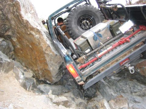 1994 Ford Bronco - This vehicle appears to be stuck while navigating a rocky terrain, with its rear end tilted upwards.