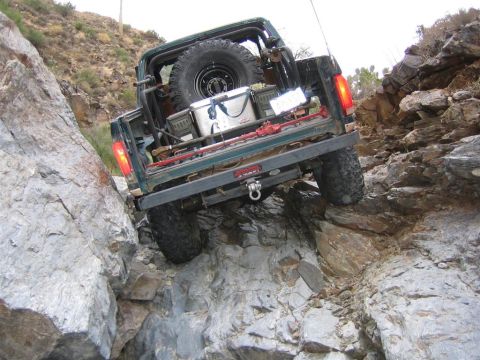 1994 Ford Bronco - A green SUV navigates a steep, rocky incline off-road.