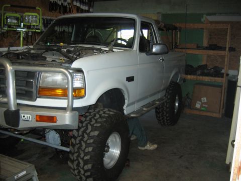 1992 Ford Bronco - White 1992 Ford Bronco undergoing work in a garage with a lifted suspension and custom bumper.