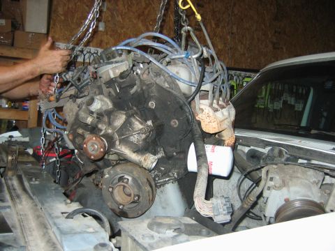 1992 Ford Bronco - An engine is being removed from a vehicle with the help of chains and a hoist.