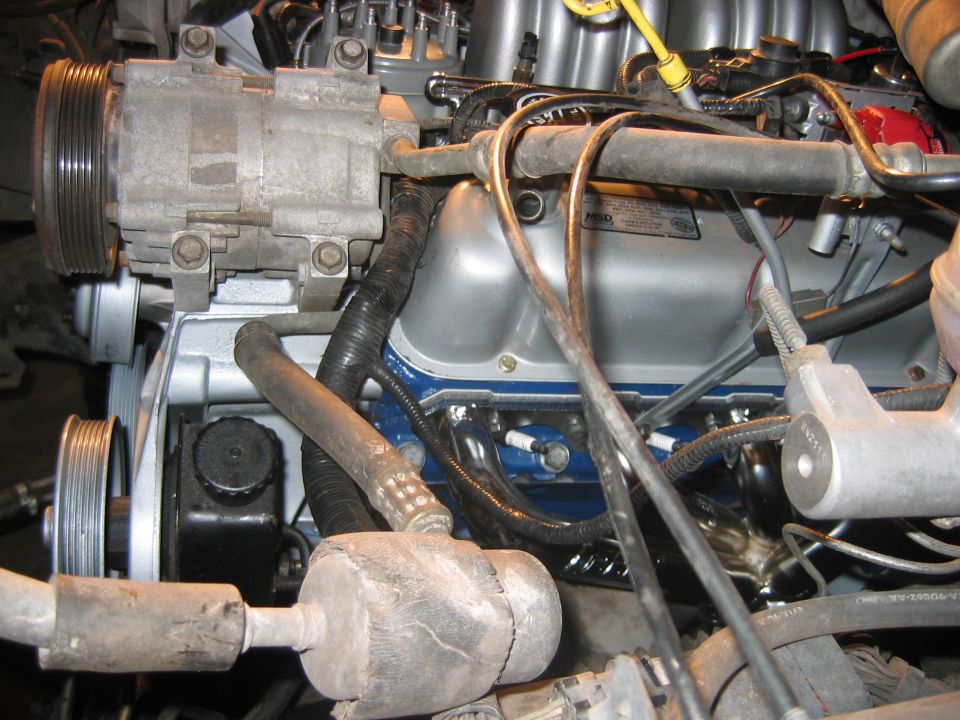 Engine bay close-up with A/C compressor, blue valve covers, and MSD component