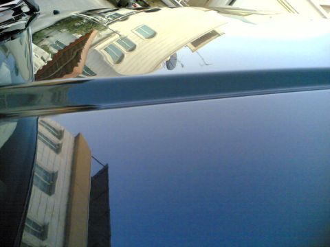 2000 Mitsubishi Montero - Reflections of buildings are visible on the glossy surface of a dark blue vehicle's hood.