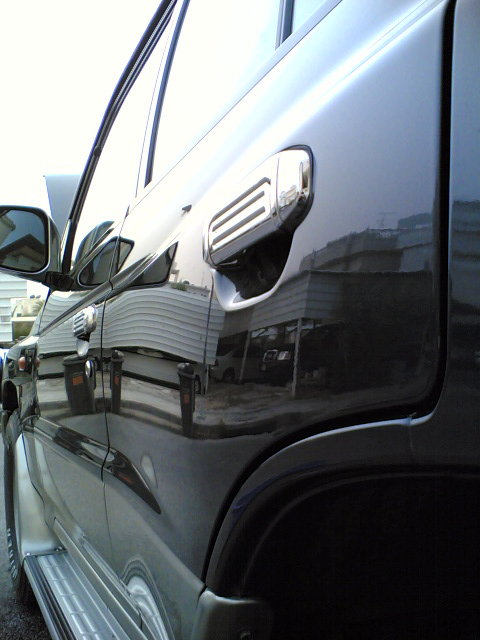 2000 Mitsubishi Montero - Close-up of the side of a dark-colored SUV, focusing on the door handle and bodywork.