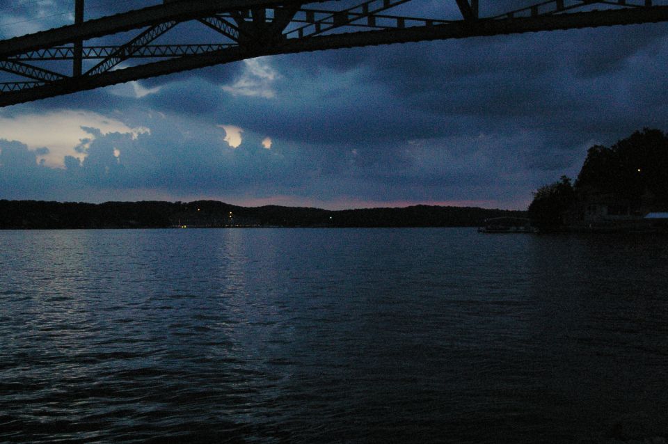 Lake and bridge structure at dusk with dark clouds overhead