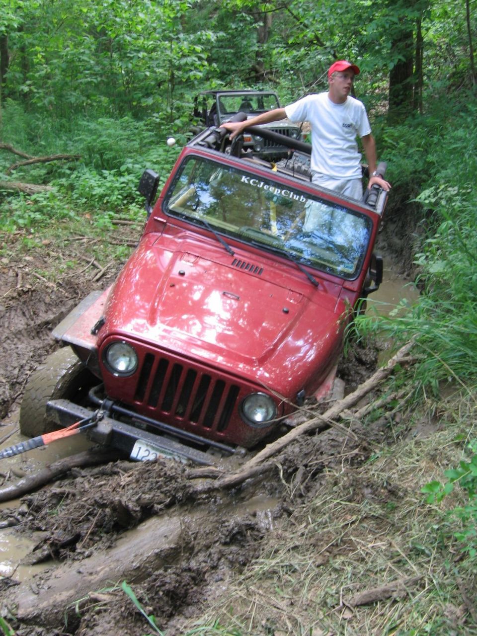 Red Jeep Wrangler TJ stuck in mud, with another Jeep behind it
