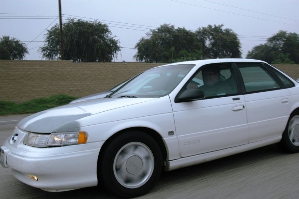 1991 Ford Taurus sedan driving on a highway, front passenger side view