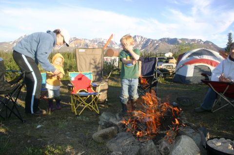 2003 Jeep TJ - A family enjoys a campfire at a campsite with a Jeep Wrangler and tents set up.