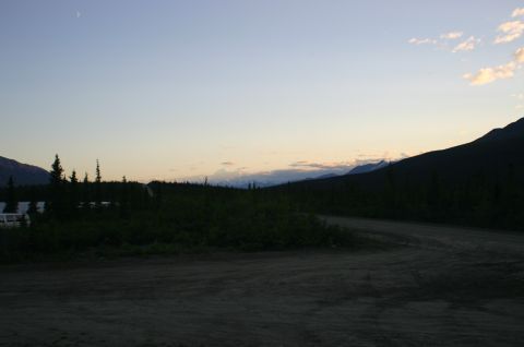2003 Jeep TJ - Mountain landscape with a dirt road and trees at dusk, with a crescent moon visible.