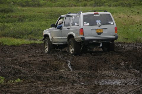 2003 Jeep TJ - Jeep Cherokee XJ navigating a muddy trail during an off-road excursion.