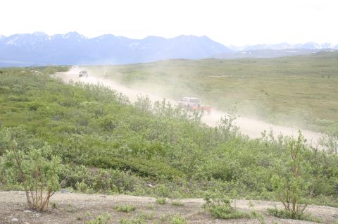 2003 Jeep TJ - Vehicles kick up dust on a remote road, with mountains visible in the distance.