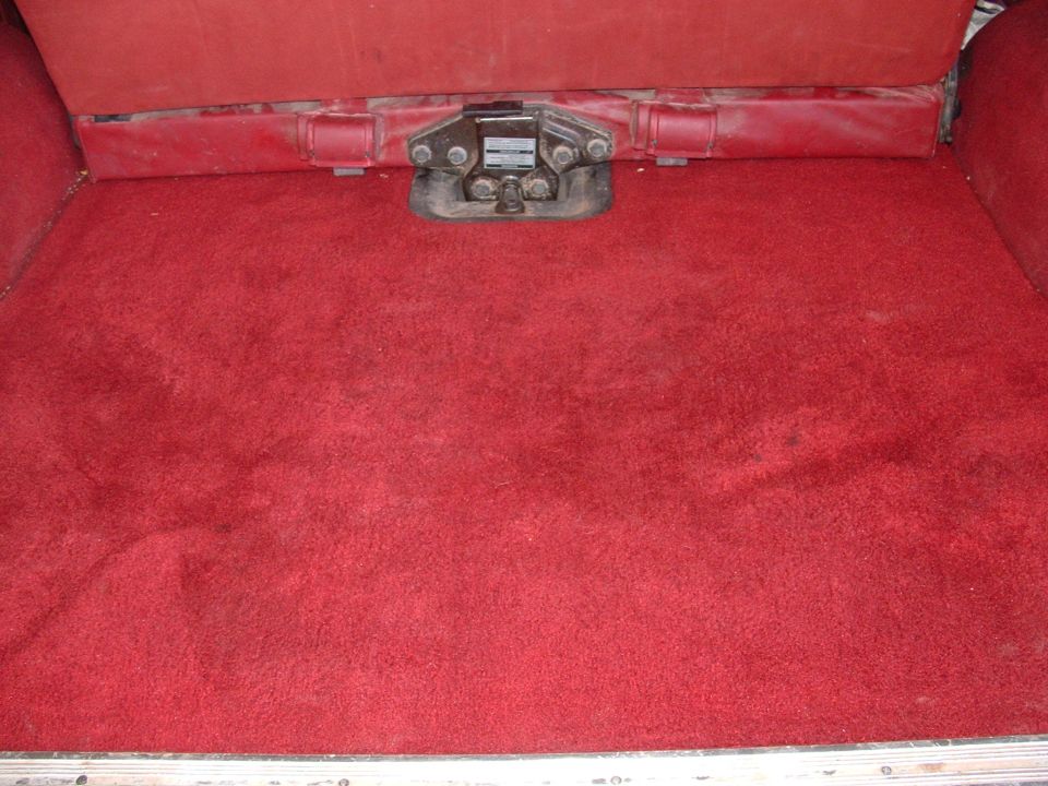 Red carpeted cargo area with a metal latch mechanism visible on the floor