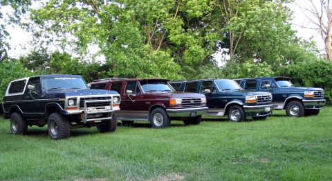 1978 Ford Bronco - A 1978 Ford Bronco is parked in front of three later model Ford SUVs on a grassy area with trees in the background.