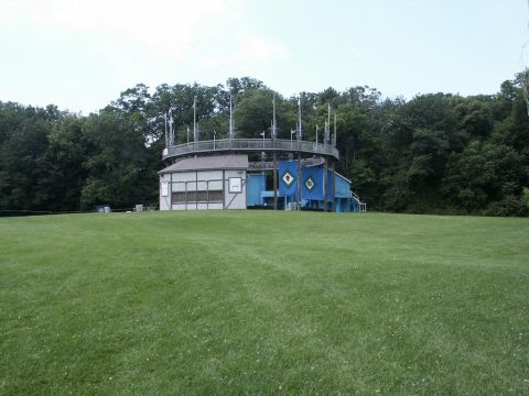 2001 Mercury Grand Marquis - A unique building with a circular elevated walkway and blue decorative elements is surrounded by a manicured lawn and dense trees.