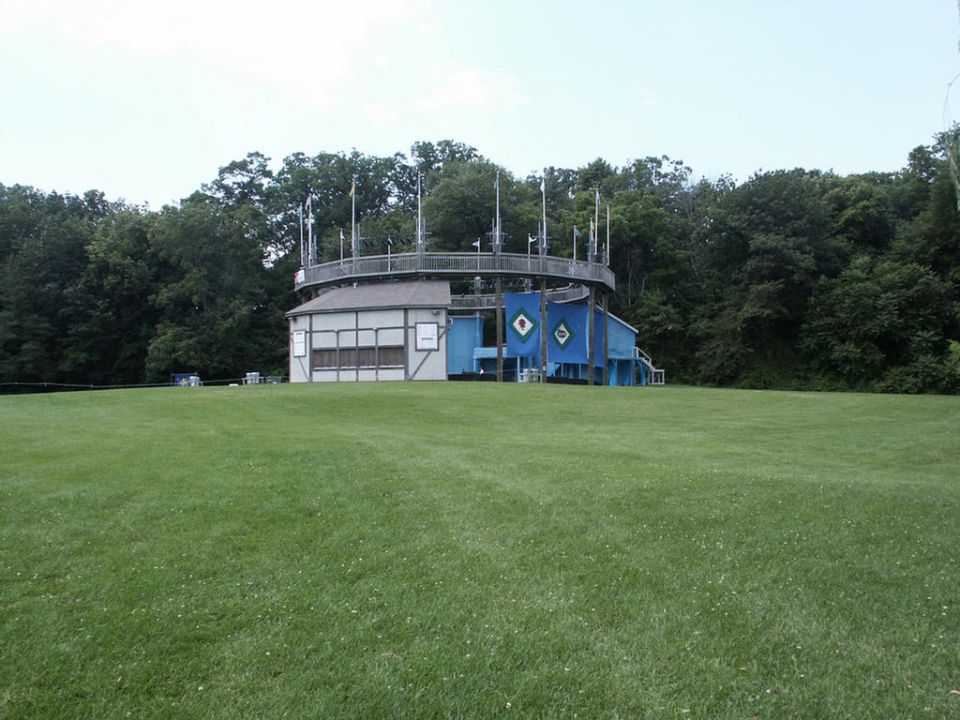 Building with a circular walkway and blue accents, set against a backdrop of trees