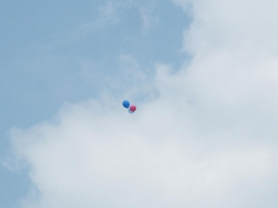three balloons floating in a cloudy sky