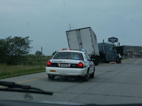 2001 Mercury Grand Marquis - A police car is parked behind a semi-truck that appears to be involved in an accident.