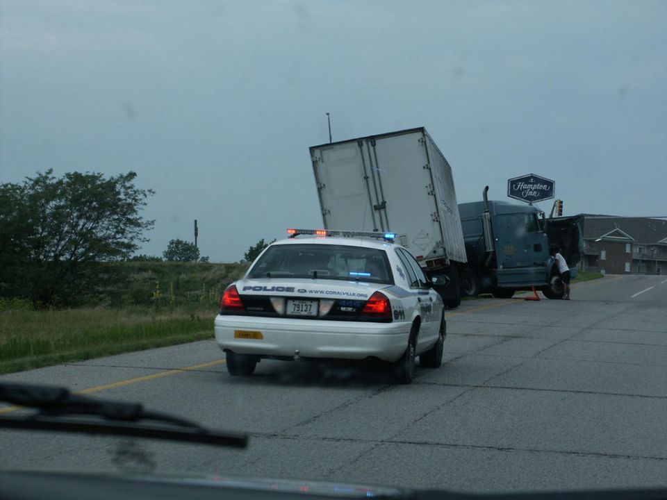 Police car at scene of semi-truck accident. Truck trailer is tilted