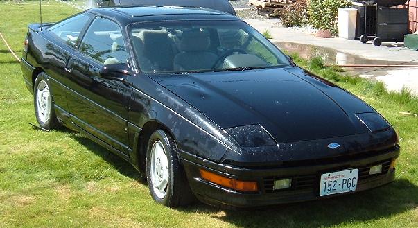 Black 1991 Ford Probe GT Turbo coupe with pop-up headlights parked on grass